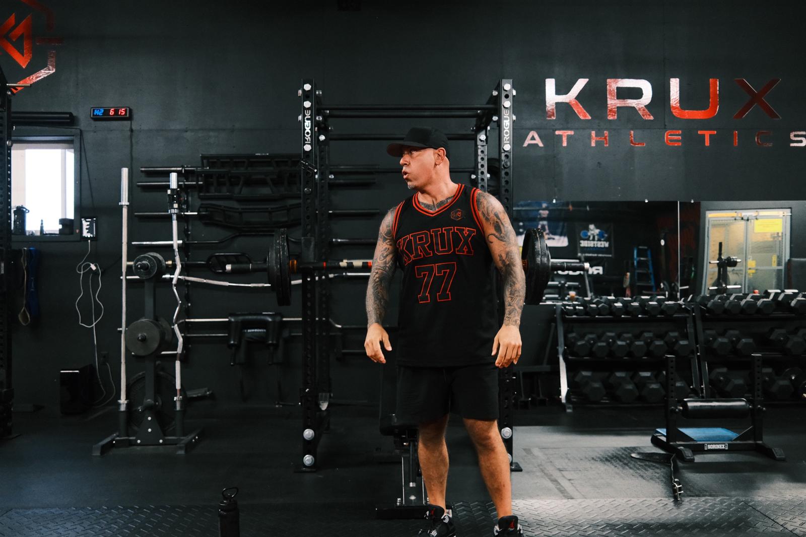 Chris Carrabino in a KRUX number 77 jersey on the gym floor at KRUX Athletics
